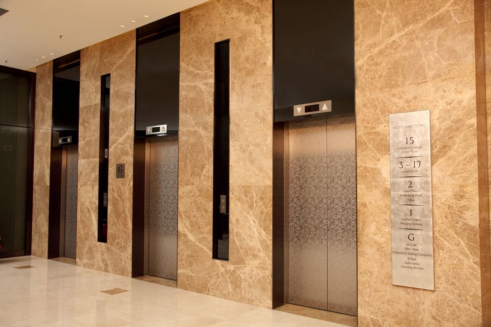 Marble-clad elevator lobby with stainless steel passenger lifts, Bengaluru